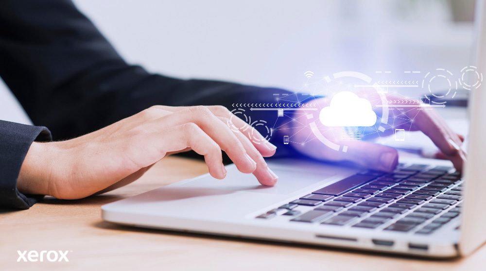 Sono raffigurate le mani di una persona che digita sulla tastiera di un computer portatile, con un'icona luminosa a forma di nuvola e connessioni di rete sovrapposte all'immagine, a simboleggiare la connettività cloud e i flussi di lavoro digitali.