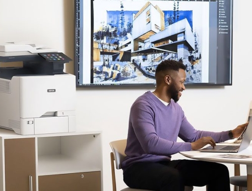 Uomini che lavorano su un computer portatile davanti a una stampante multifunzione a colori Xerox® VersaLink® C415