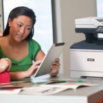 Stampante multifunzione Xerox® VersaLink® B415 sul posto di lavoro Due donne che utilizzano un tablet davanti a una stampante multifunzione Xerox® VersaLink® B415